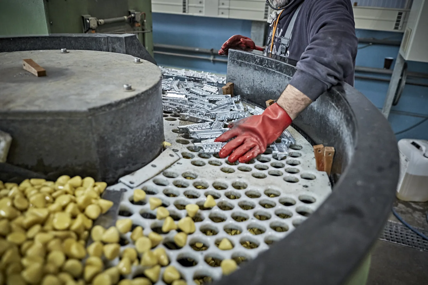 Mitarbeiter an einer Gleitschleifanlage bei der Bearbeitung von Metallteilen