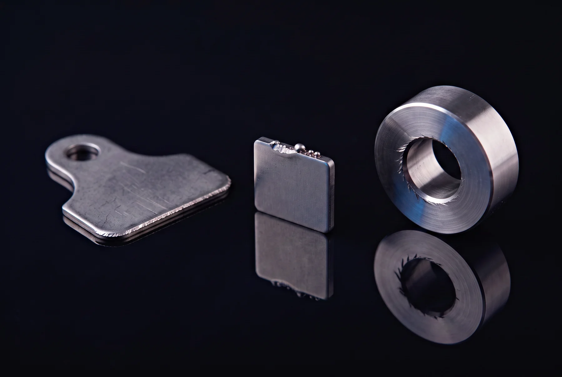 Visualisierung typischer Grate an Blechkante, geschnittenem Metallteil und bearbeiteter Bohrung