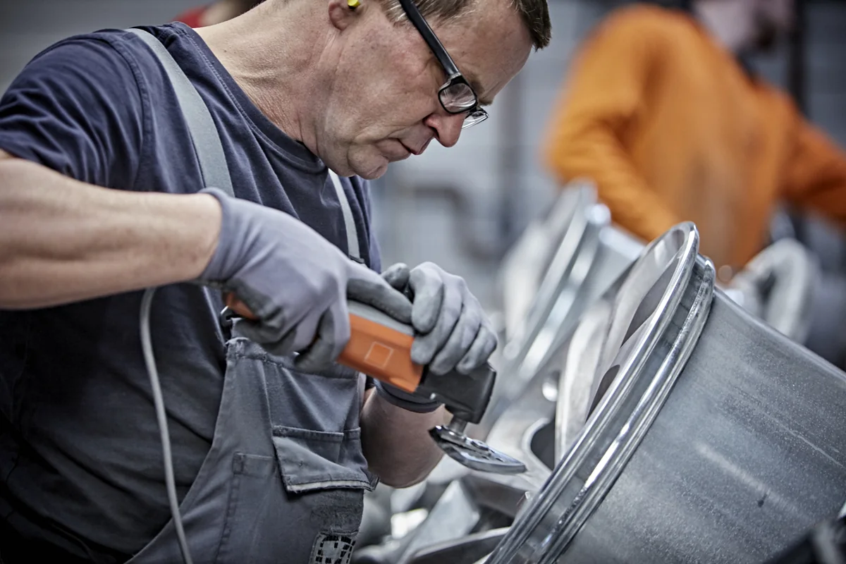 Mitarbeiter bei der manuellen Kantenbearbeitung eines Metallbauteils