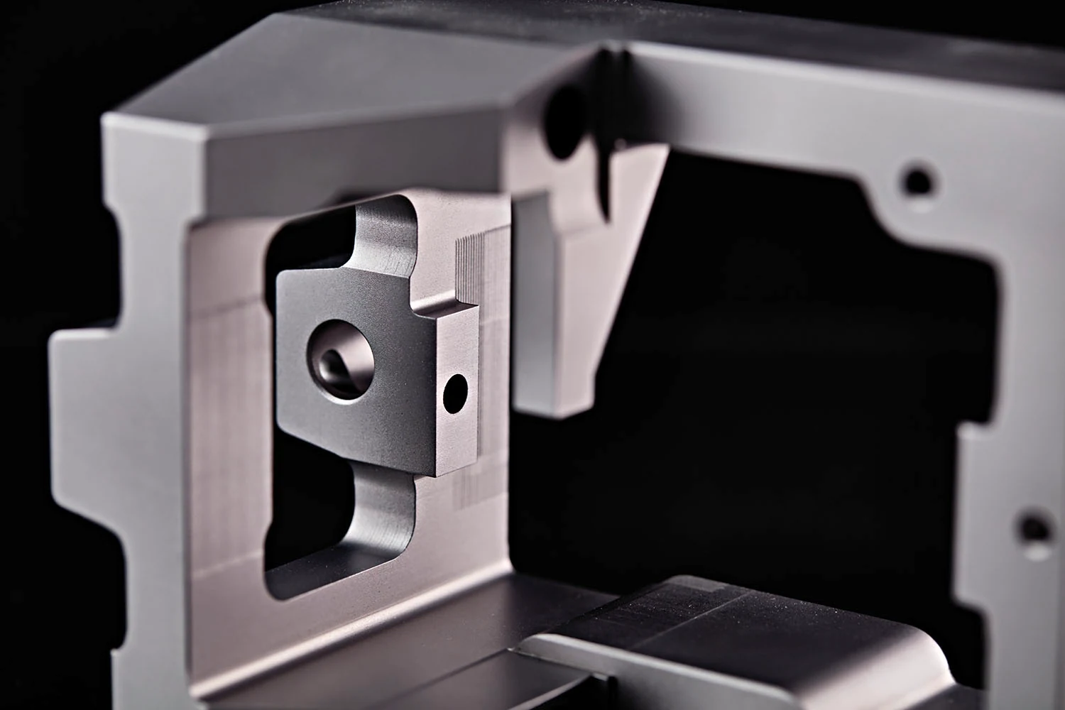 Nahaufnahme eines metallischen Bauteils mit Bohrung, Kanten und vertiefter Kontur